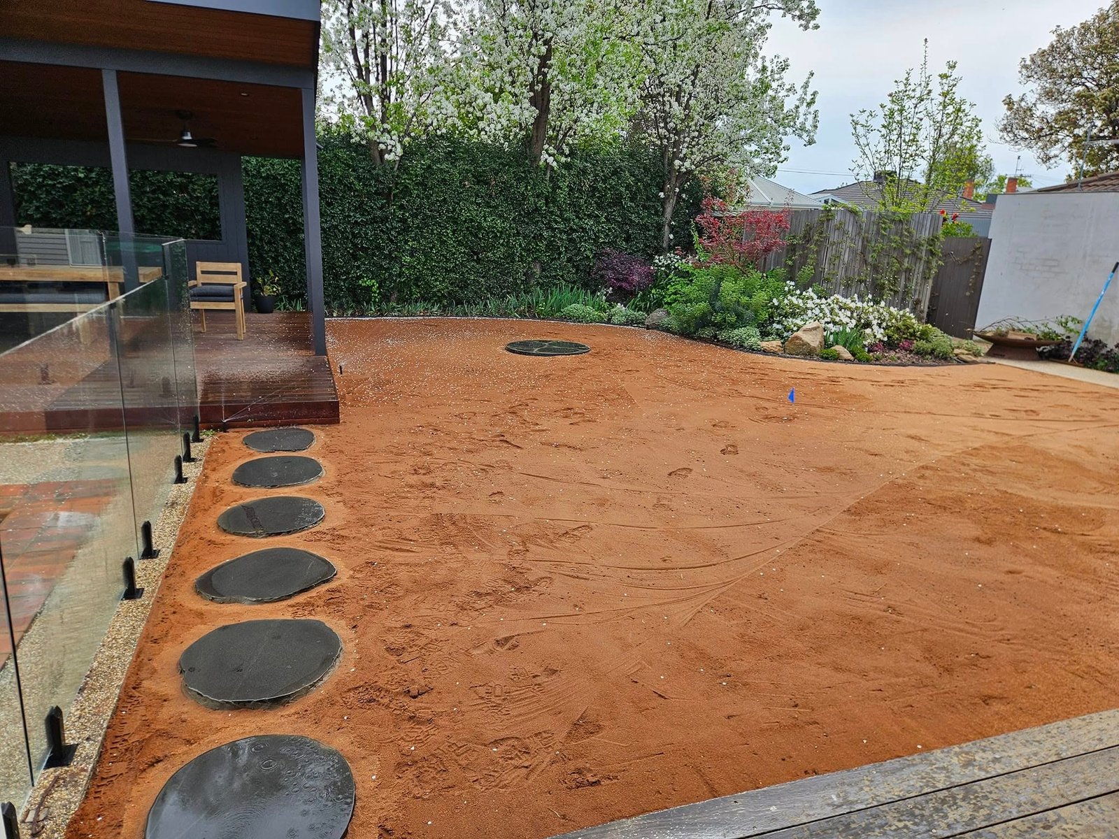 Levelled backyard with stepping stones and sprinkler outlets prepared before turf installation.