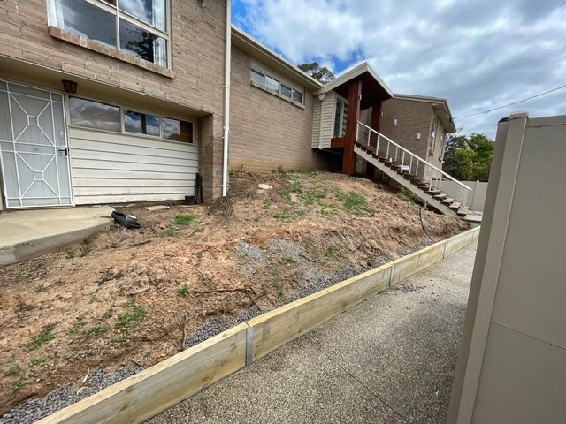 Dry and sparsely planted garden bed beside a driveway before landscaping in Shepparton.
