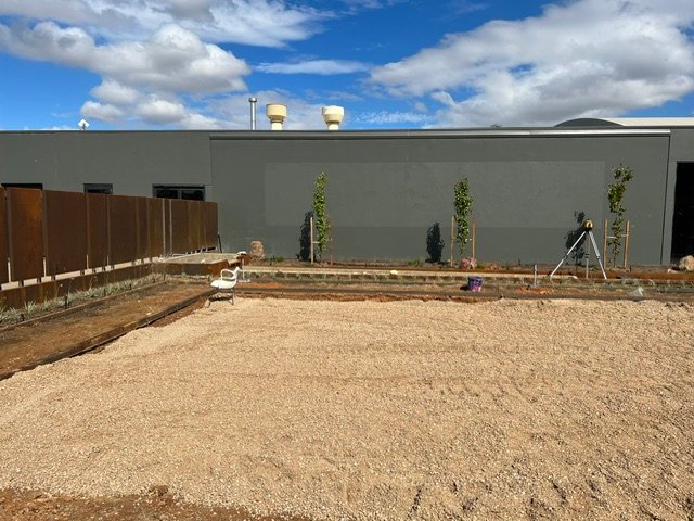 Gravel surfacing being installed across the central outdoor area.