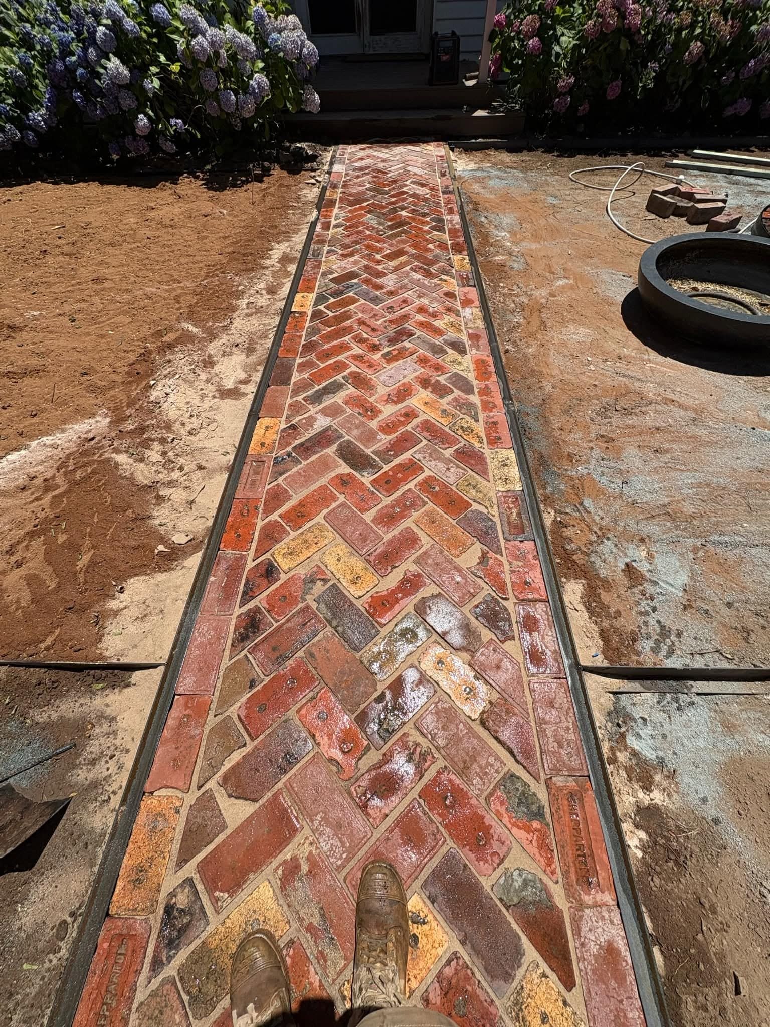 Close view of the completed red-brick herringbone front path.